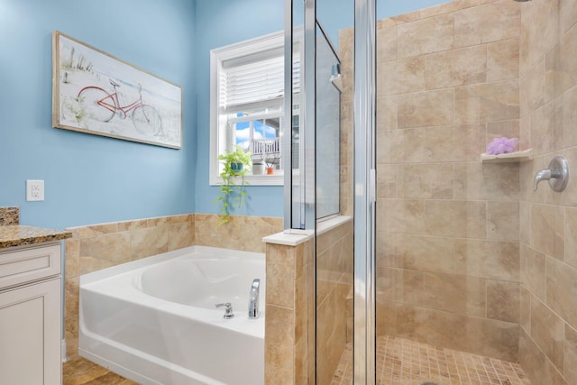 bathroom featuring a stall shower, a garden tub, and vanity