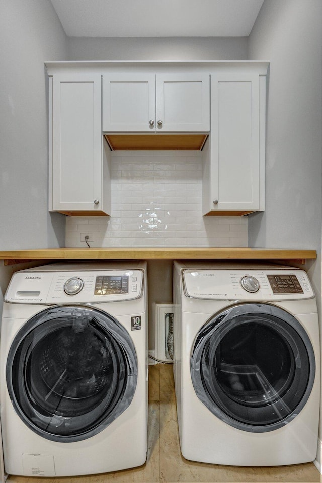 clothes washing area featuring washing machine and clothes dryer and cabinet space