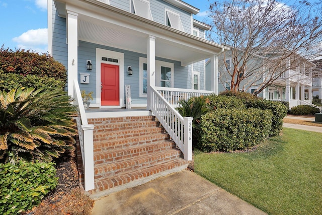 doorway to property with covered porch and a lawn