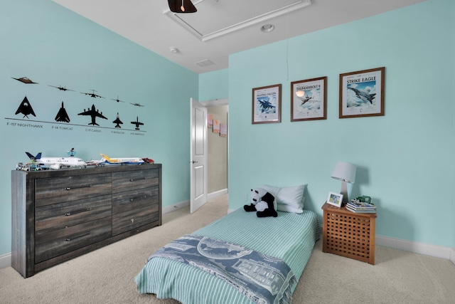 carpeted bedroom featuring attic access, baseboards, and a ceiling fan