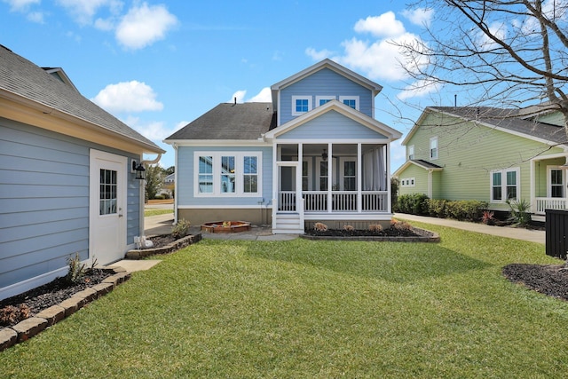 rear view of property featuring a yard, roof with shingles, and a sunroom