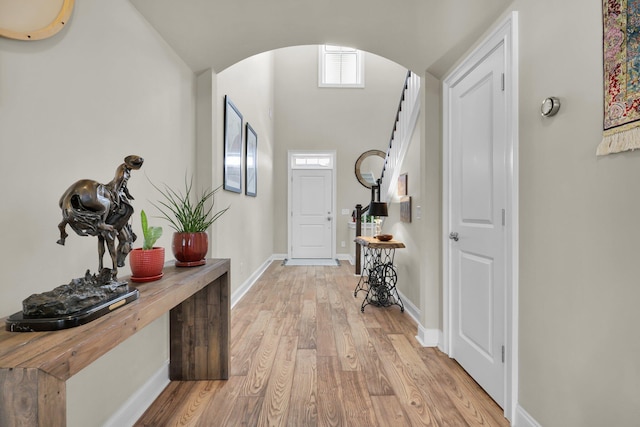 interior space featuring arched walkways, visible vents, baseboards, light wood-style floors, and stairway