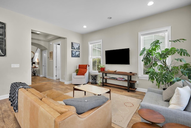 living area featuring light wood finished floors, arched walkways, and a wealth of natural light