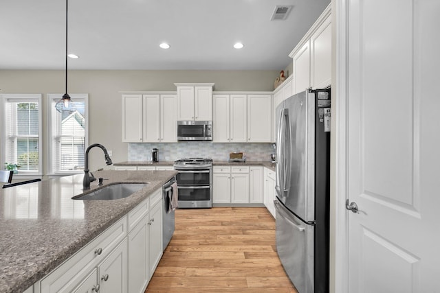 kitchen featuring white cabinets, visible vents, stainless steel appliances, and a sink