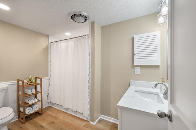 full bathroom featuring vanity, a textured ceiling, shower / bathtub combination with curtain, hardwood / wood-style floors, and toilet