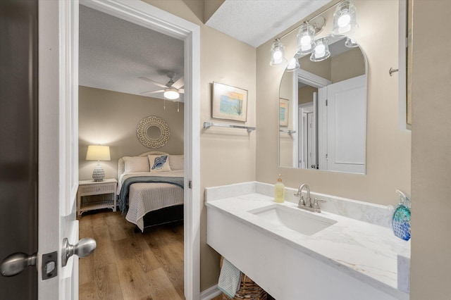 bathroom with hardwood / wood-style flooring, ceiling fan, a textured ceiling, and vanity