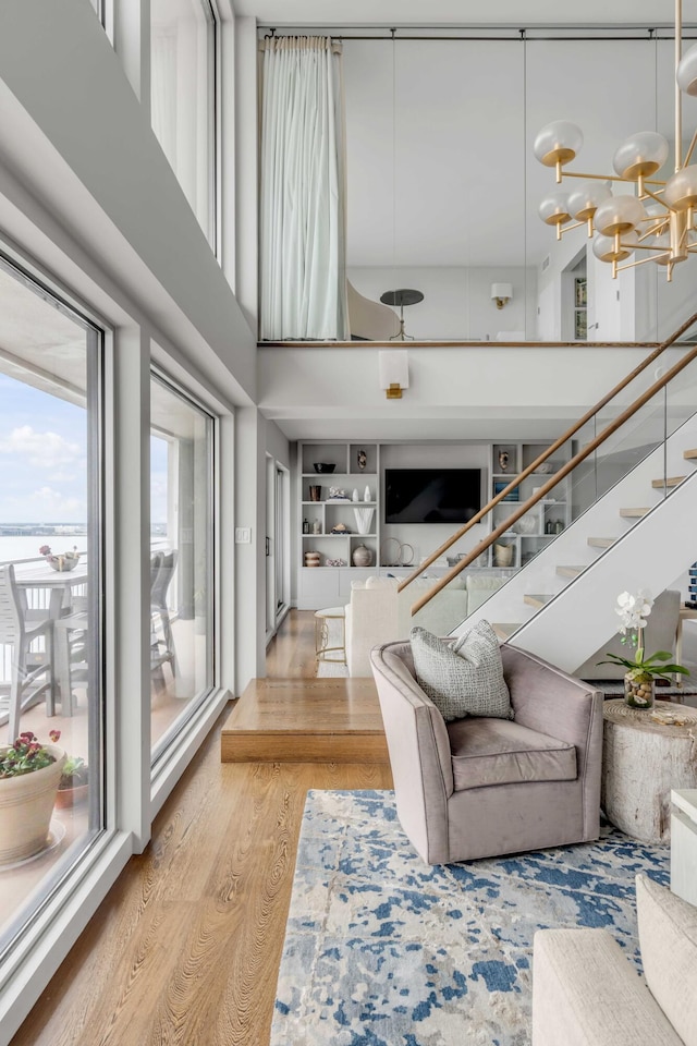 330 Concord St Unit 18F, Charleston, SC 29401 - living room with built in features, stairway, a chandelier, a high ceiling, and light wood-style floors