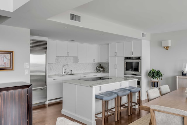 330 Concord St Unit 18F, Charleston, SC 29401 - kitchen with a sink, visible vents, dark wood finished floors, a kitchen bar, and appliances with stainless steel finishes