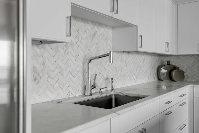 330 Concord St Unit 18F, Charleston, SC 29401 - kitchen featuring decorative backsplash, white cabinets, a sink, and light stone countertops