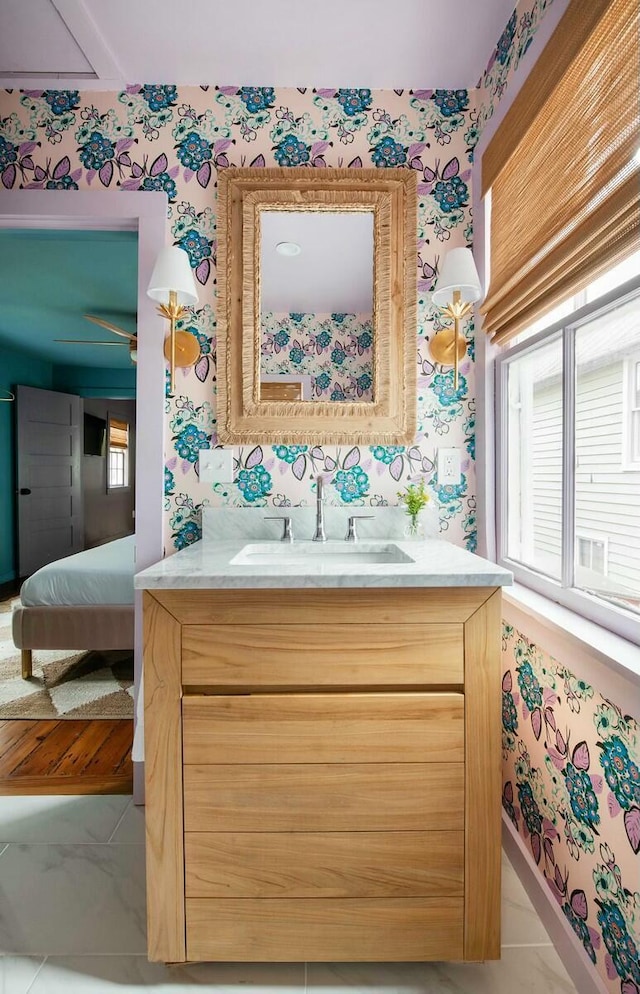 bathroom with connected bathroom, vanity, baseboards, and wallpapered walls