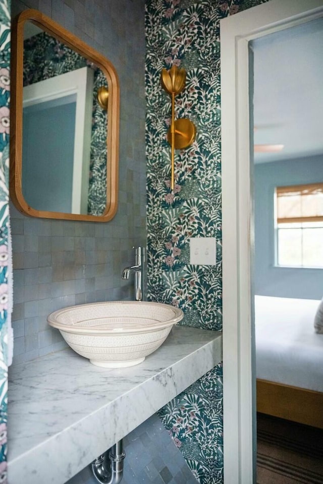 bathroom featuring a sink, decorative backsplash, and wallpapered walls