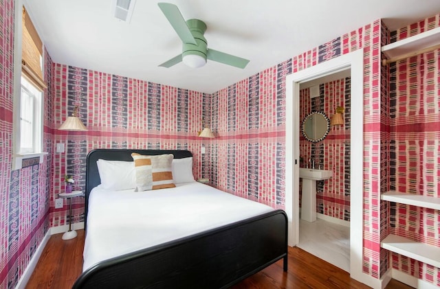 bedroom featuring ceiling fan, dark wood-style flooring, visible vents, and wallpapered walls