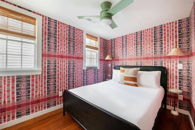 bedroom featuring visible vents, wood finished floors, a ceiling fan, and baseboards