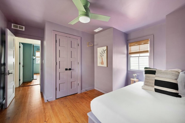 bedroom with light wood-style floors, baseboards, visible vents, and a ceiling fan