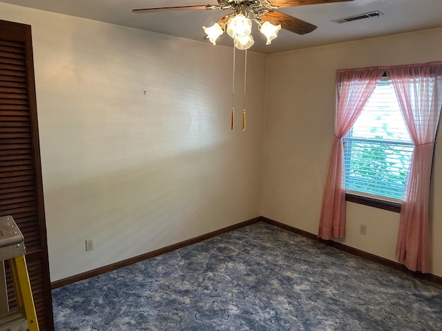unfurnished room featuring dark carpet, a ceiling fan, baseboards, and visible vents