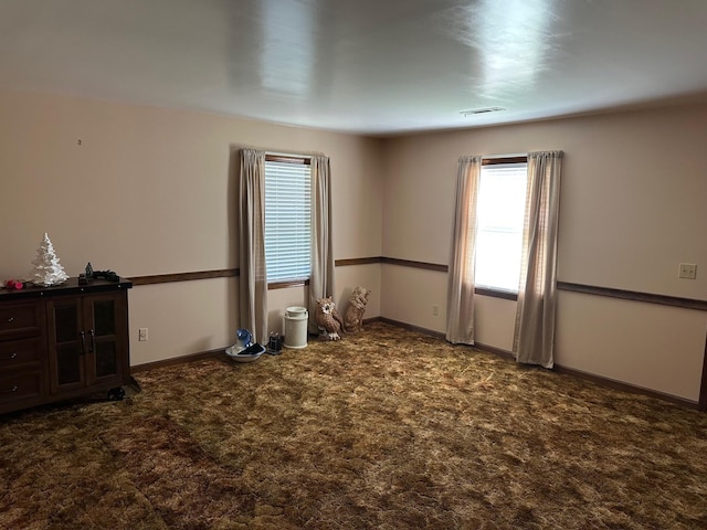 carpeted spare room featuring plenty of natural light and visible vents