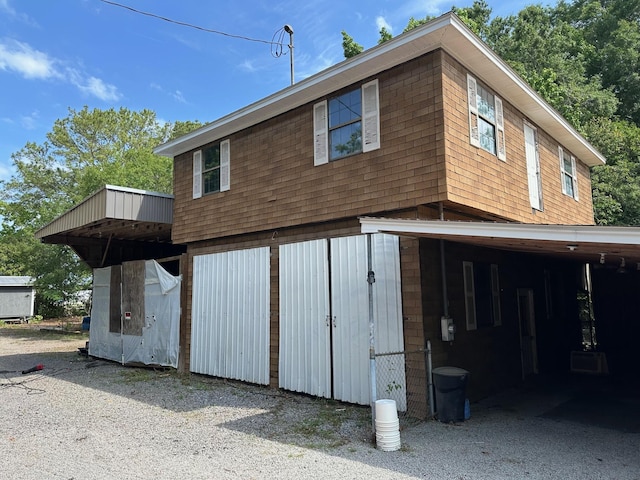 rear view of property with a garage and gravel driveway
