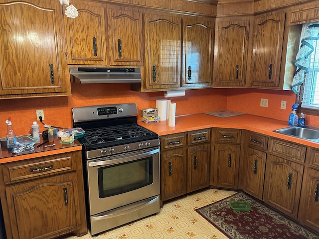 kitchen featuring stainless steel range with gas stovetop, extractor fan, a sink, and light countertops