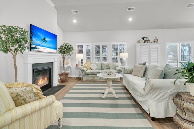 living room with plenty of natural light, light hardwood / wood-style floors, and lofted ceiling