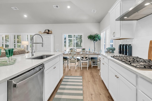 kitchen featuring white cabinetry, sink, wall chimney range hood, backsplash, and appliances with stainless steel finishes