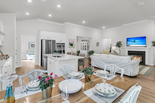 dining space featuring light hardwood / wood-style flooring, crown molding, and sink