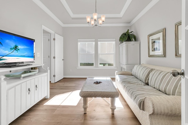 living room featuring an inviting chandelier, light wood-type flooring, and a tray ceiling