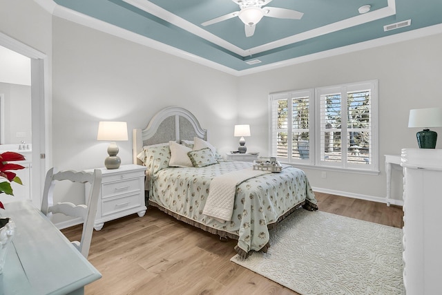 bedroom featuring a raised ceiling, ceiling fan, and light hardwood / wood-style floors