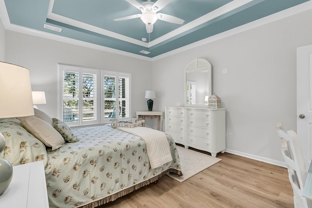 bedroom featuring ceiling fan, a raised ceiling, and light hardwood / wood-style flooring