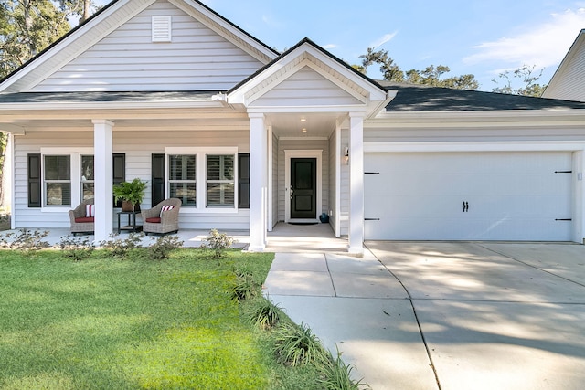 view of front of home with covered porch, a garage, and a front lawn