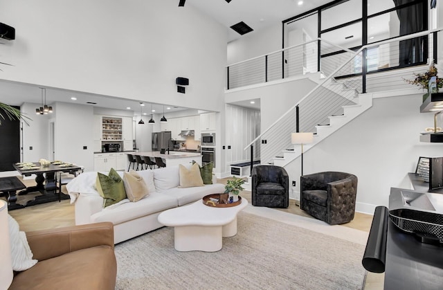 living area featuring a towering ceiling, stairway, and recessed lighting