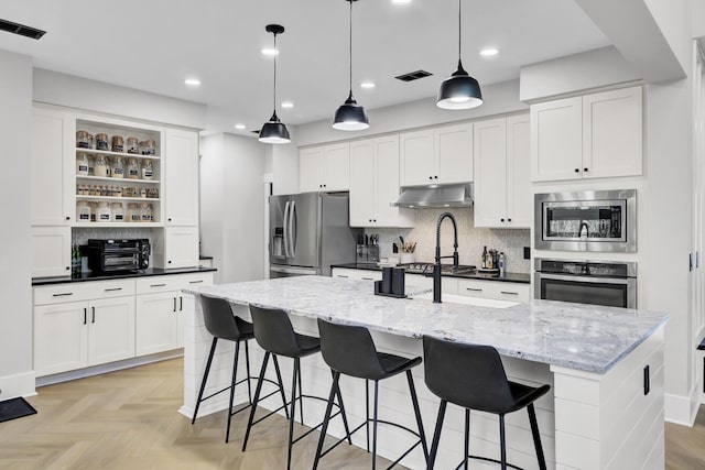 kitchen with under cabinet range hood, visible vents, appliances with stainless steel finishes, and open shelves