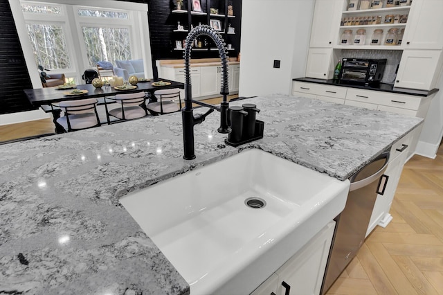 kitchen featuring open shelves, a sink, white cabinetry, and light stone countertops