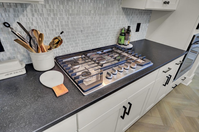 kitchen with stainless steel gas cooktop, white cabinets, and decorative backsplash