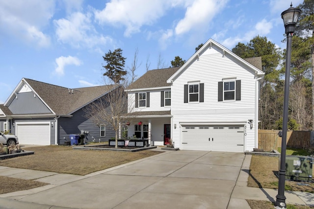 traditional home with a shingled roof, driveway, and fence