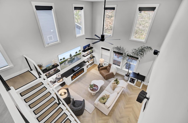 living room with a ceiling fan, a high ceiling, and baseboards