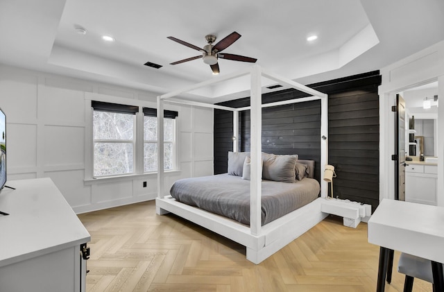 bedroom with recessed lighting, a raised ceiling, visible vents, and a decorative wall