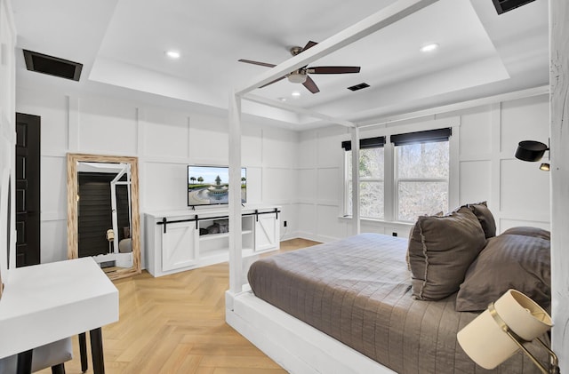 bedroom with recessed lighting, a raised ceiling, and a decorative wall