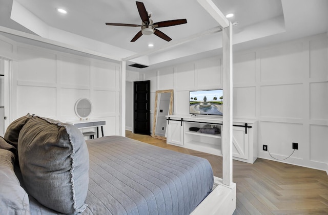 bedroom with a tray ceiling, a decorative wall, and recessed lighting