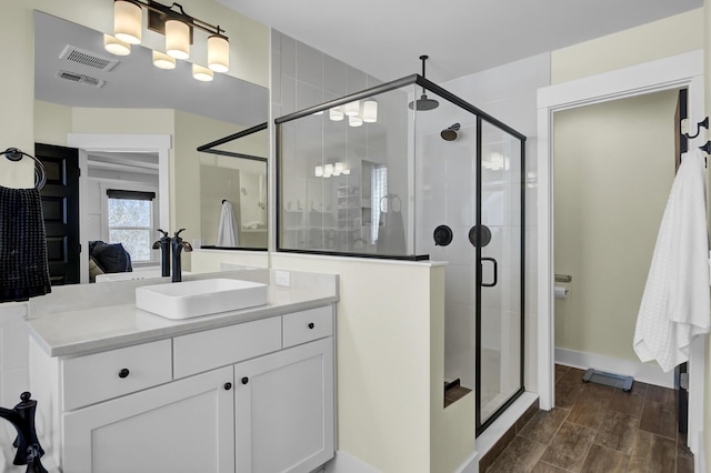 full bathroom with a stall shower, visible vents, vanity, and wood finished floors