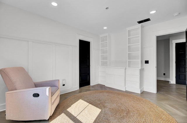 sitting room with visible vents, a decorative wall, built in features, and recessed lighting