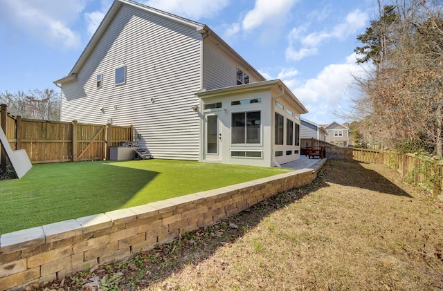 back of house featuring a fenced backyard, central AC, and a yard