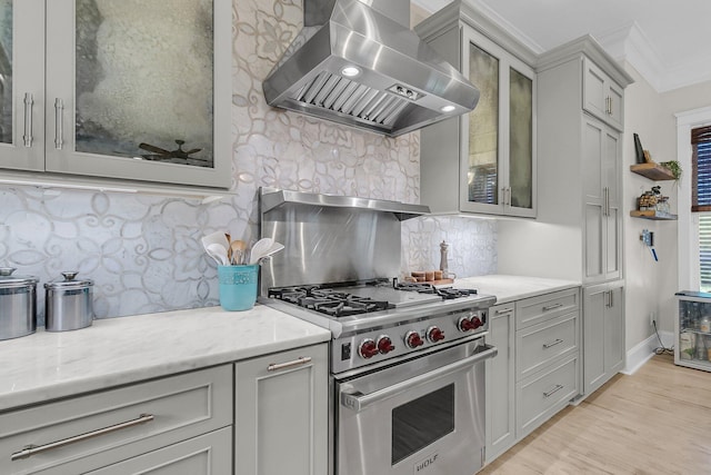 kitchen with wall chimney range hood, designer stove, decorative backsplash, crown molding, and light wood-type flooring