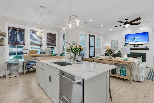 kitchen featuring a sink, dishwasher, light wood-style flooring, a kitchen island with sink, and white cabinets