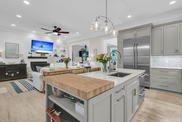 kitchen featuring gray cabinets, a sink, open shelves, crown molding, and a ceiling fan