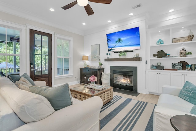 living area featuring a ceiling fan, ornamental molding, a fireplace with flush hearth, recessed lighting, and light wood-type flooring