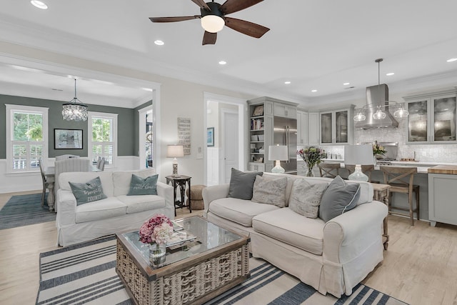 living room with a chandelier, light wood-style flooring, a ceiling fan, recessed lighting, and ornamental molding
