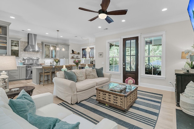 living area with crown molding, a ceiling fan, recessed lighting, light wood-style flooring, and baseboards