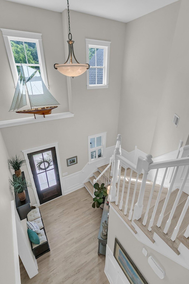 foyer entrance featuring plenty of natural light, wood finished floors, a wainscoted wall, stairs, and a towering ceiling