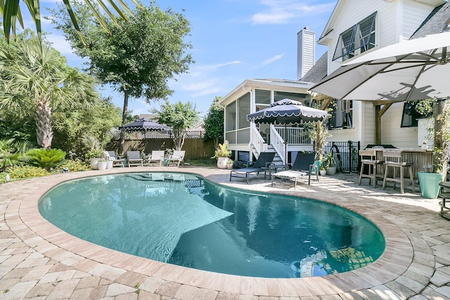 view of pool featuring a sunroom, a patio area, and fence