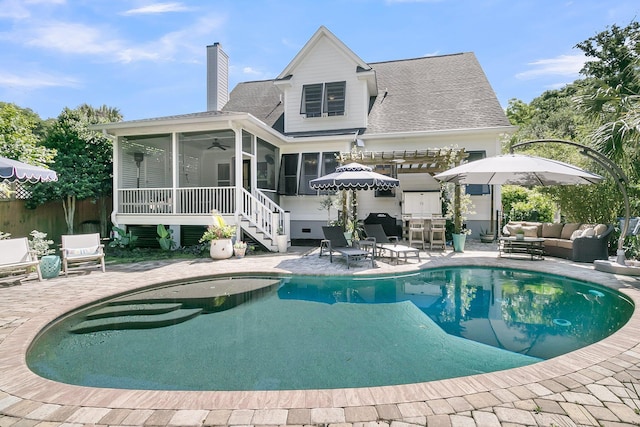 rear view of house featuring a sunroom, an outdoor hangout area, a chimney, a patio area, and a ceiling fan